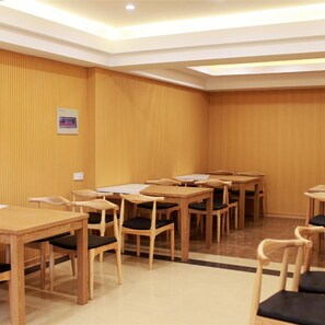 Une salle de conférence avec plusieurs tables et chaises en bois, un tableau blanc et un petit panneau accroché au mur.