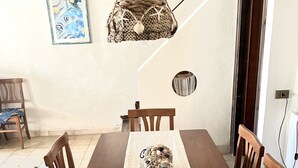 En matplats med ett träbord och stolar, en hängande lampa och inramade konstverk på väggen.