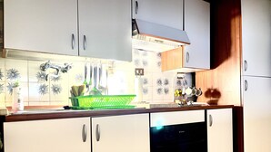 Ett kök med vita skåp, ett grönt diskställ och en diskmaskin.