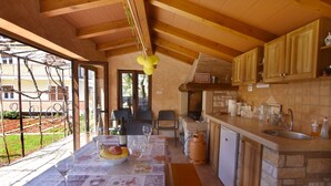 A rustic kitchen with stone countertops, wooden cabinets, and a dining area with a table set for two.