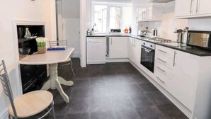 Ett modernt kök med vita skåp, ett matbord med stolar och en inbyggd ugn.
