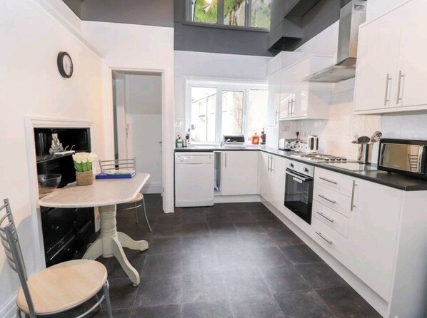 A modern kitchen with white cabinetry, a dining table with chairs, and a built-in oven.