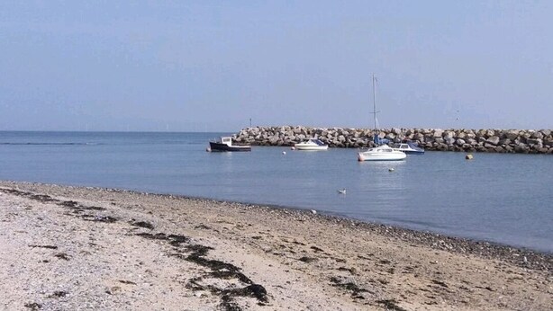 En strand med båtar som ligger ankrade nära en stenbrygga.