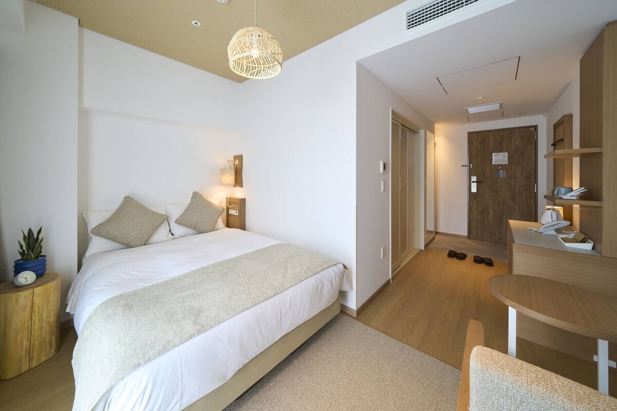 A modern bedroom with a large bed, bedside tables, a desk, and a chair.