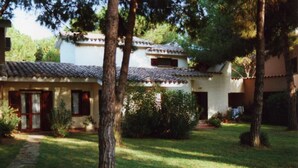 Un bâtiment traditionnel avec un toit en tuiles, entouré d’arbres et d’une pelouse bien entretenue.
