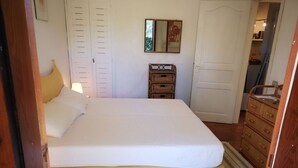 Une chambre à coucher avec un grand lit, une commode, un miroir et une porte.