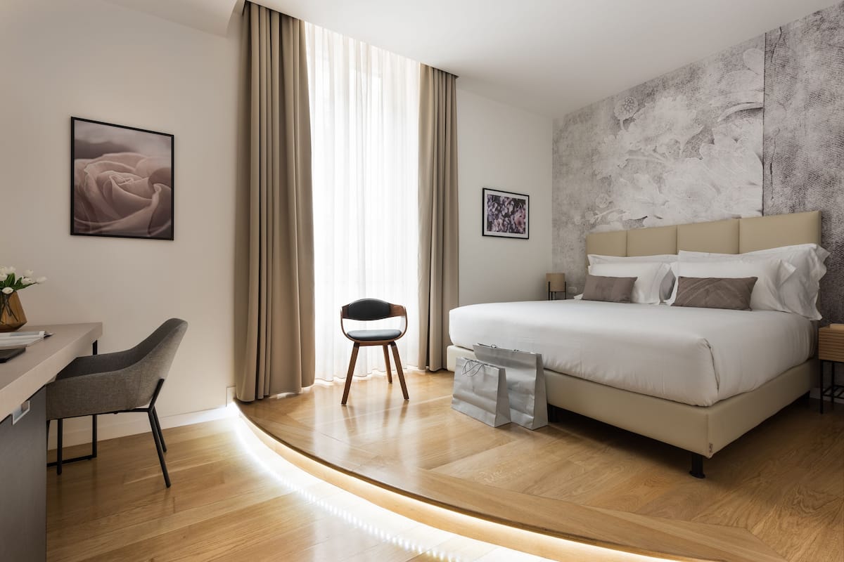 A modern hotel room with a bed, a desk, and a chair.