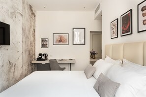 Une chambre d’hôtel moderne, dotée d’un grand lit, d’un bureau avec une chaise et d’un téléviseur à écran plat fixé au mur.