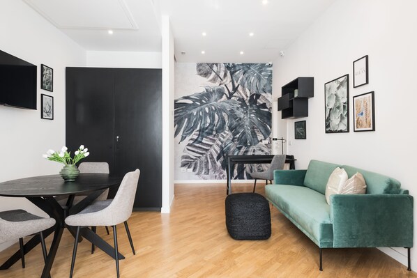 Un salon moderne avec une table à manger en bois foncé, des chaises grises, un canapé turquoise et un pouf noir.