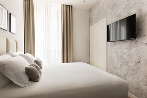 A bedroom with a bed, curtains, a TV mounted on the wall, and framed pictures on the wall. - At 41 Luxury Suites & Rooms (Rome)