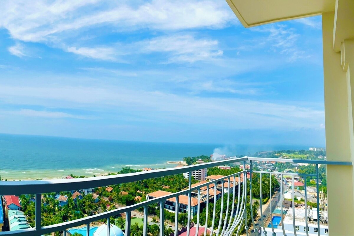 A balcony with a view of the ocean and a resort area.