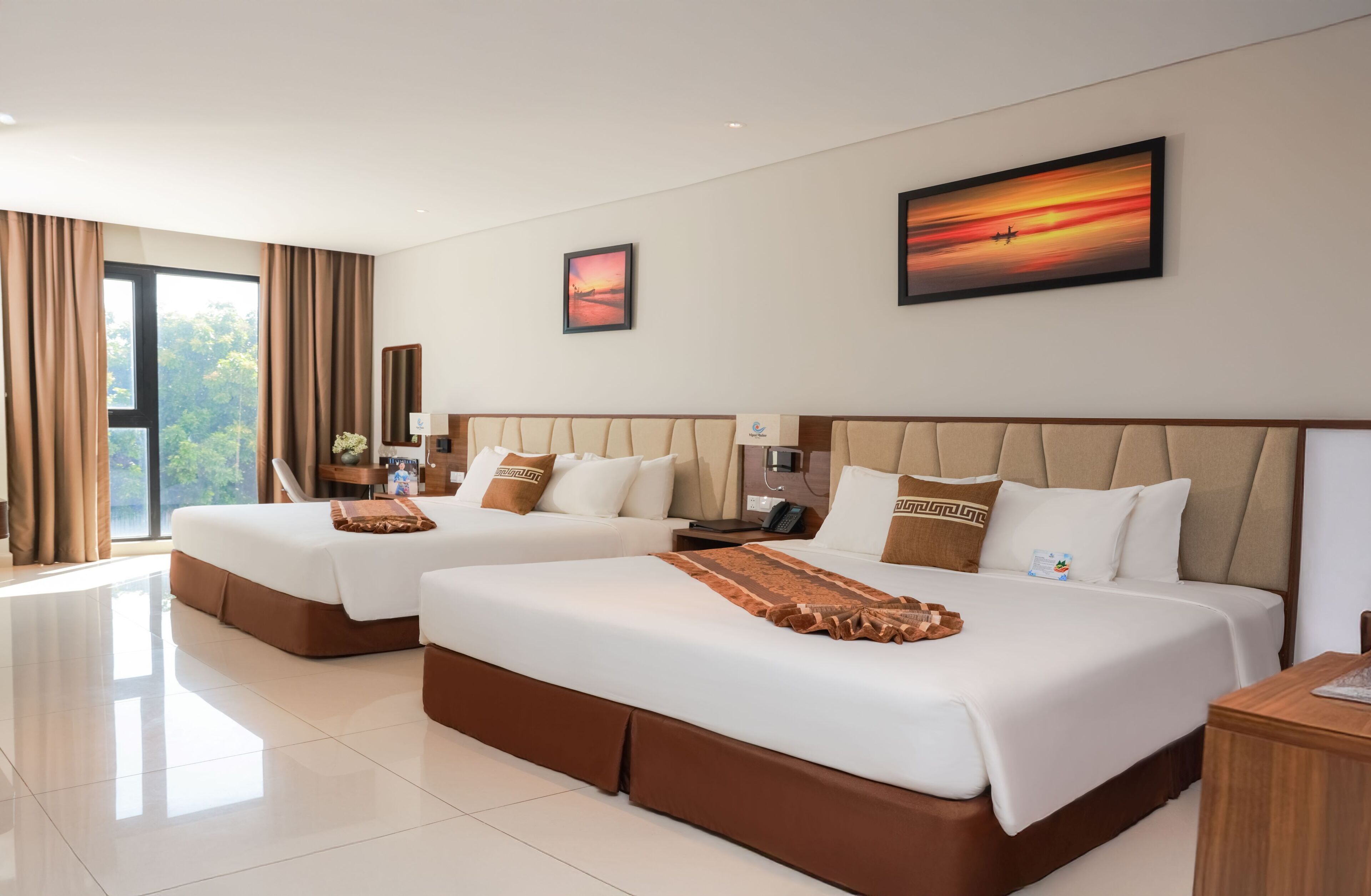 A hotel room with two beds, a large window with curtains, a painting on the wall, and a nightstand with a lamp.