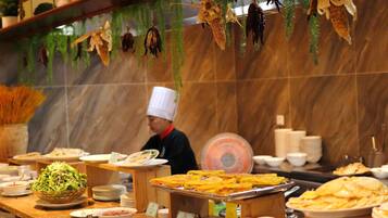 A buffet setup with various dishes and a chef in uniform.