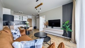 Uma sala de estar moderna com sofá, mesa de centro, TV e área de jantar com mesa e cadeiras.