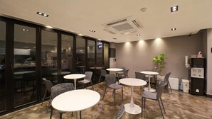 A modern indoor space with round tables and chairs, a large window, and a ceiling air conditioning unit. - HOTEL RUBATO RB (Daegu)