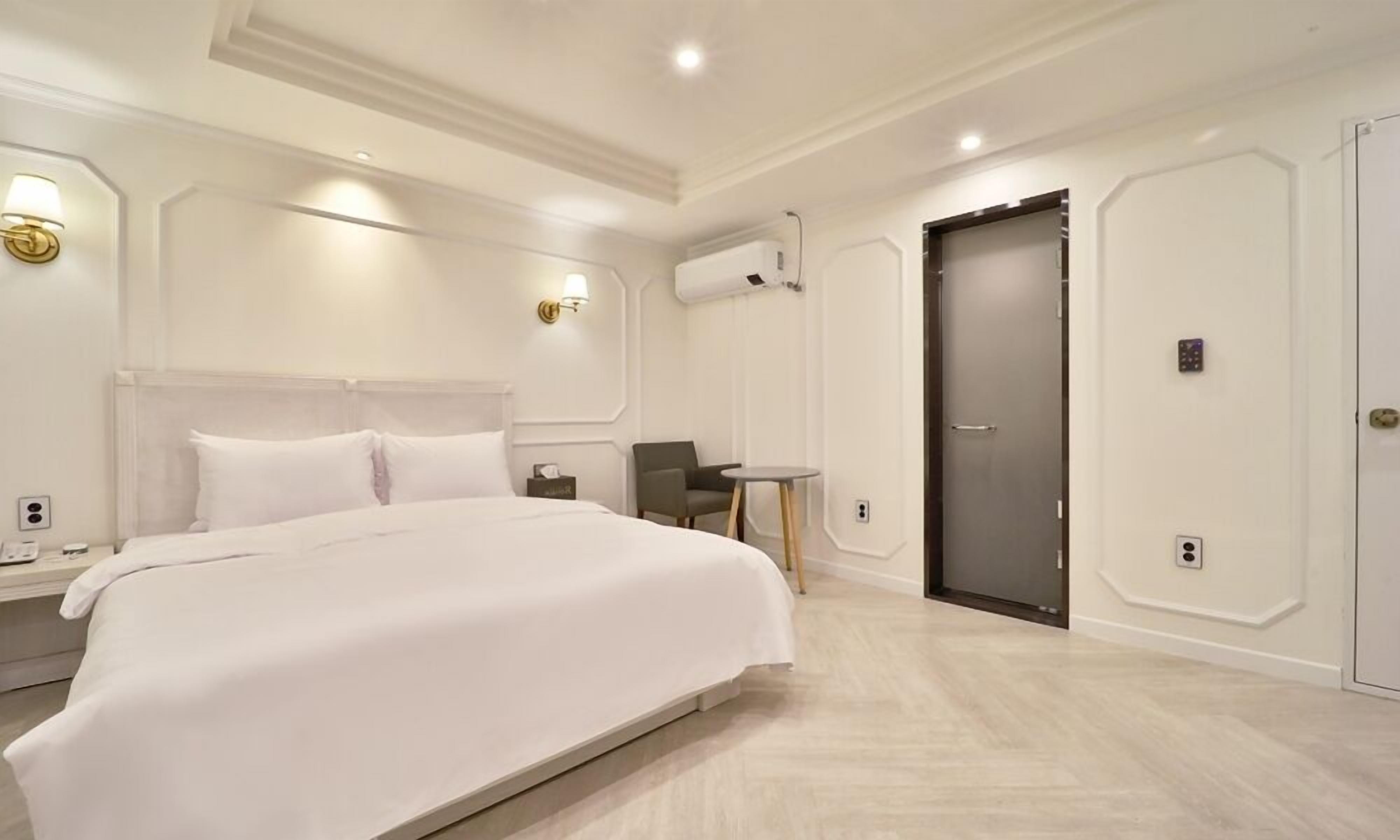 Una habitación de hotel moderna con una cama grande, una mesita y una puerta.