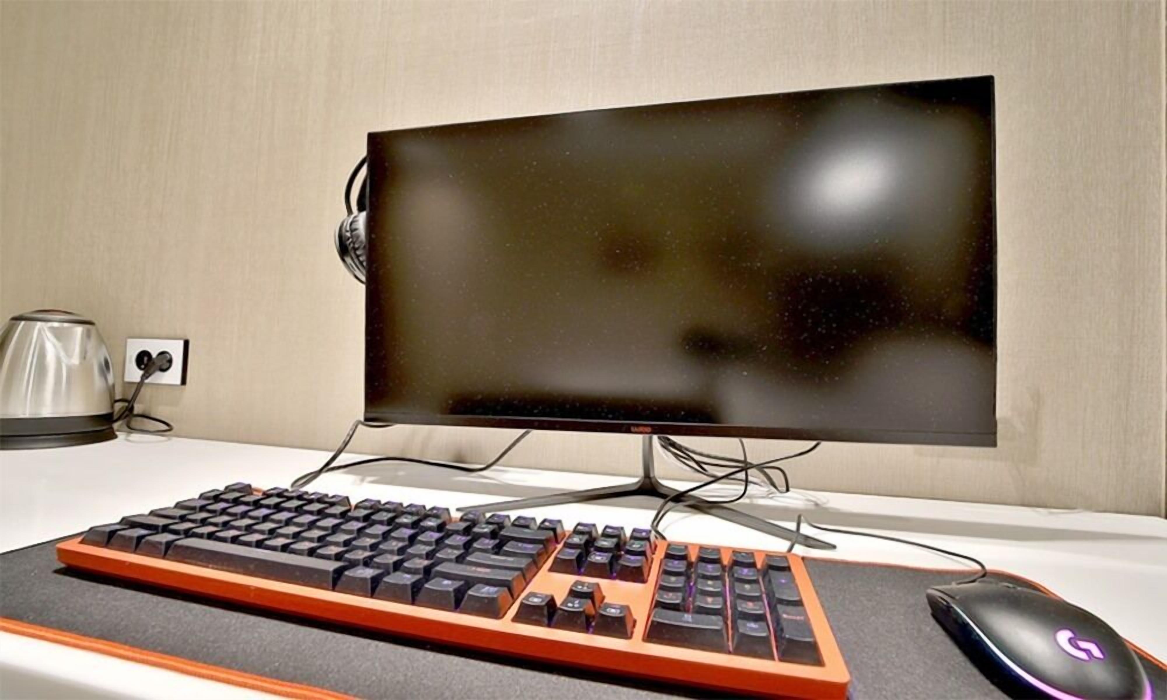 Een computerinrichting met toetsenbord, monitor en muis op een bureau.
