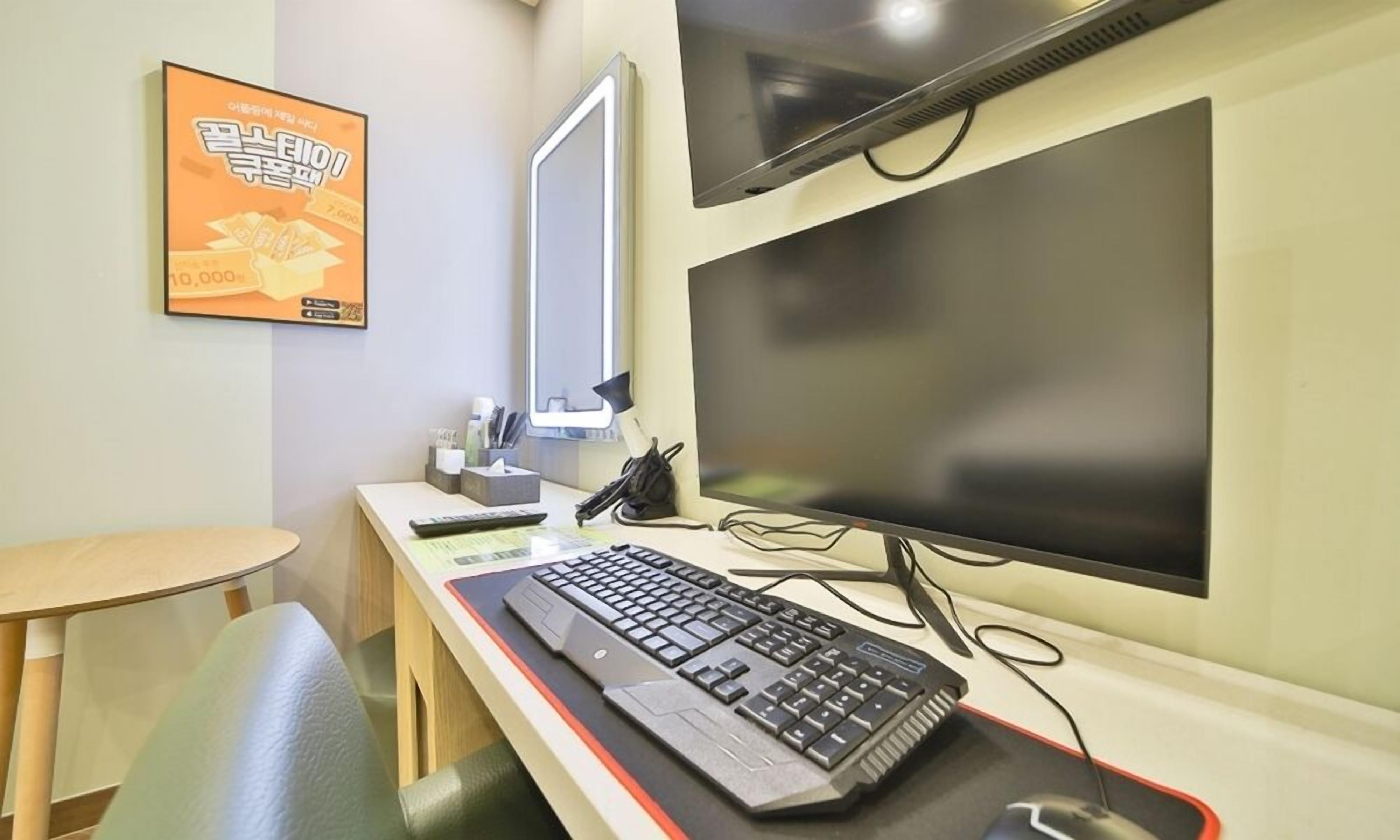 A modern office setup with a desk, computer, keyboard, and a large monitor.