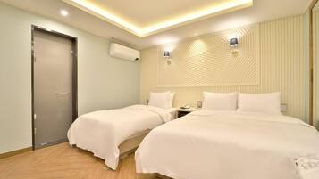 Habitación de hotel con dos camas, una puerta, un equipo de aire acondicionado y una lámpara fijada a la pared.