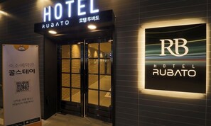 A hotel entrance with a sign reading "HOTEL RUBATO" and a QR code on a poster.