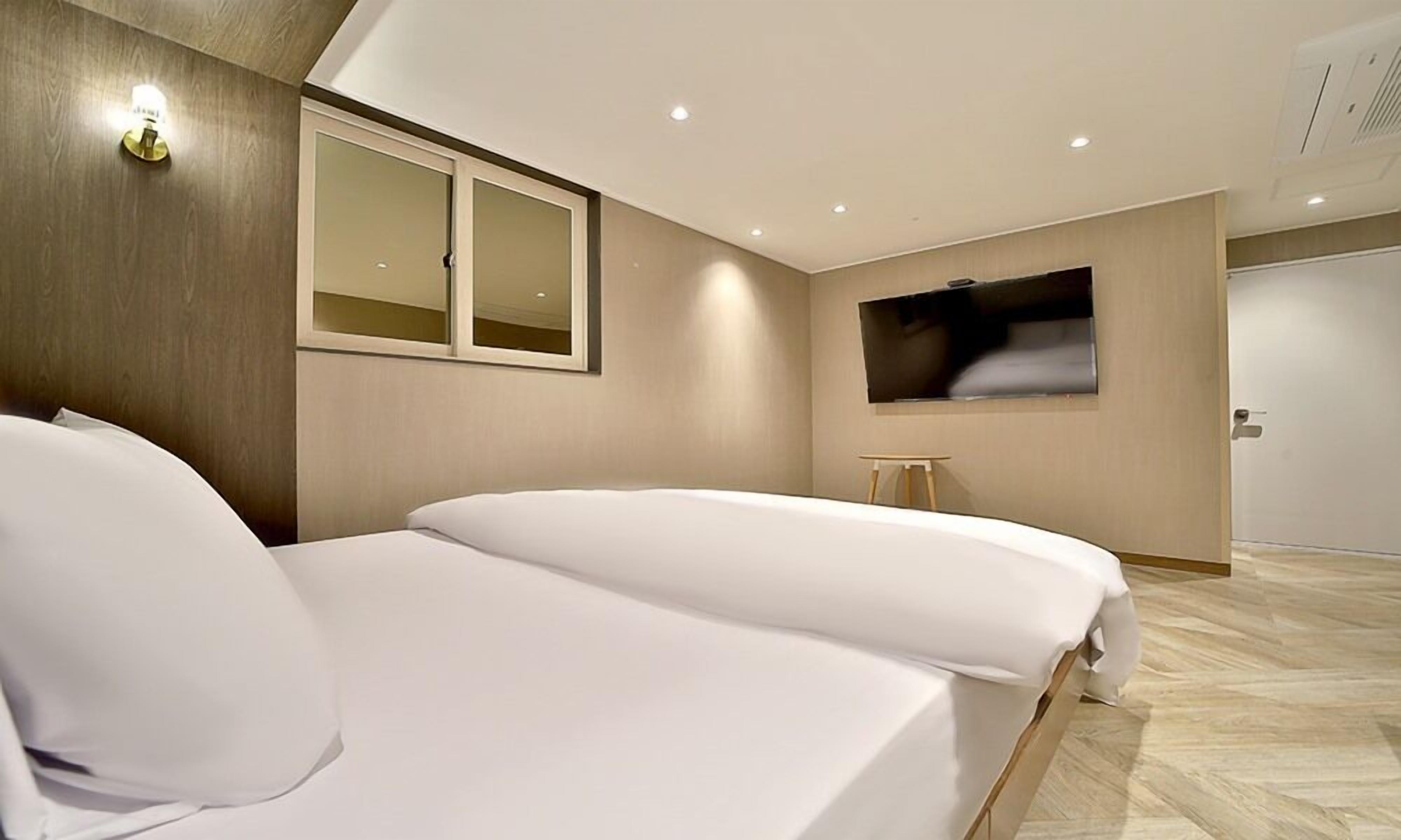 Een moderne hotelkamer met twee bedden, een groot raam en een flatscreen-televisie.
