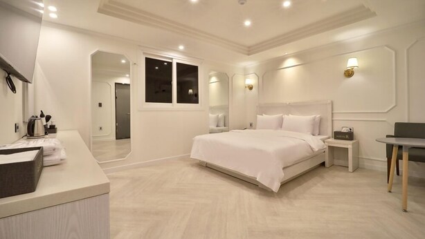 A modern hotel room with a large bed, a bedside table, a small table, and a mirror. - HOTEL RUBATO RB (Daegu)