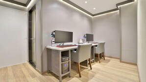 A modern, well-lit room with two desks, each equipped with a computer, keyboard, and headphones. The room features a minimalist design with neutral walls and a wooden floor. - HOTEL RUBATO RB (Daegu)