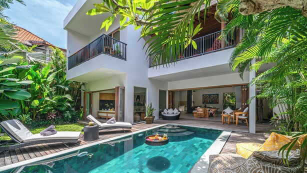 A modern two-story building with a swimming pool, outdoor seating, and lush greenery. - Puri Aman - Unique & Lush 3BR Pool Villa - Next to Gigi Susu & Walk to Beach (Canggu)