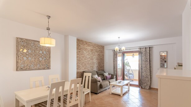 Un comedor con una mesa, sillas, un sofá y una mesa auxiliar. Cuenta con un panel decorativo y una araña.