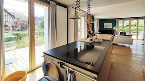 Een moderne keuken met een zwart aanrecht, roestvrijstalen apparatuur en een hangende lamp.