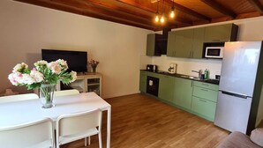 Una cocina compacta con armarios verdes, un refrigerador blanco y una zona de comedor con una mesa y sillas.