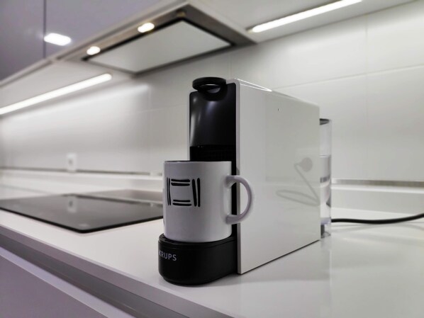 A coffee machine with a mug on its base, placed on a white countertop.