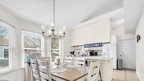 A modern kitchen with white cabinets, a welcome sign, and a chandelier. - West Destin!  3 blks to beach! Front & back porch! Walk to shopping/restaurants (Destin)