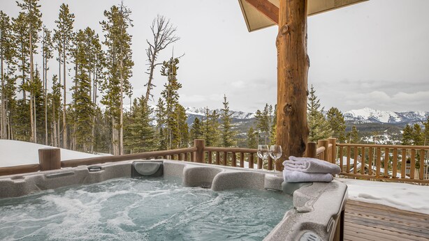 A hot tub with a wooden deck and a view of snow-capped mountains. - Ski-in/Ski-out w/private hot tub and stunning views in Cowboy Heaven - The Moose Lodge (Big Sky)
