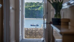 A view from a hallway leading to a bay with a boat and people on the shore. - Gwynne House - 6 Bedroom - Tenby Harbour (Tenby)