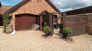 A stone building with a wooden door and a gravel driveway. - The Retreat (Watchet)