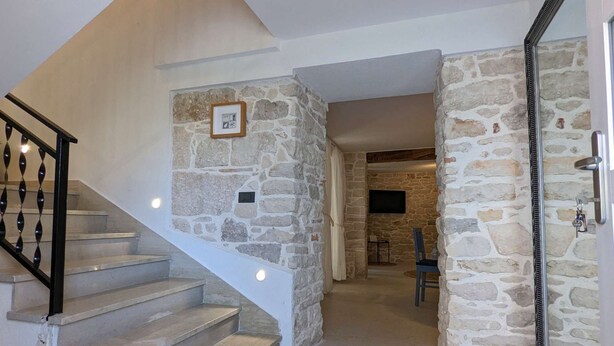 Una escalera conduce a una habitación con paredes de piedra y una puerta con un ojo de cerradura.