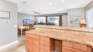 A kitchen with granite countertops, wooden cabinets, and a dining area with a table and chairs. - 4 Bedroom Home Steps from the Sand w/ Balcony&BBQ (Newport Beach)
