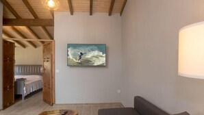 A modern living room with a large gray sofa, a wooden coffee table, and a painting of a surfer on a wave. - Sintra-Riviera by Interhome (Sintra)