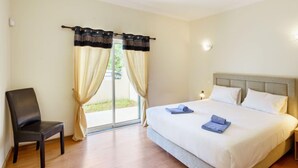 Une chambre d’hôtel avec un lit, une chaise et une porte-fenêtre coulissante avec des rideaux.
