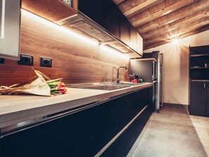 Uma cozinha moderna com painel de parede de madeira, pia embutida e geladeira de aço inoxidável.