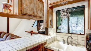 Una cocina con armarios de madera, una encimera blanca y un ventanal decorado con un copo de nieve.