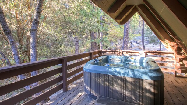 Un jacuzzi en una terraza de madera con vista a un bosque.