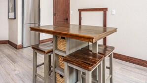 Een keuken met een houten tafel en stoelen, een roestvrijstalen koelkast en een houten deur.