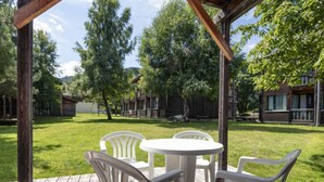 Una terraza de madera con una mesa redonda y cuatro sillas.