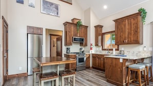 Una cocina moderna con armarios de madera, electrodomésticos de acero inoxidable y una barra con taburetes.
