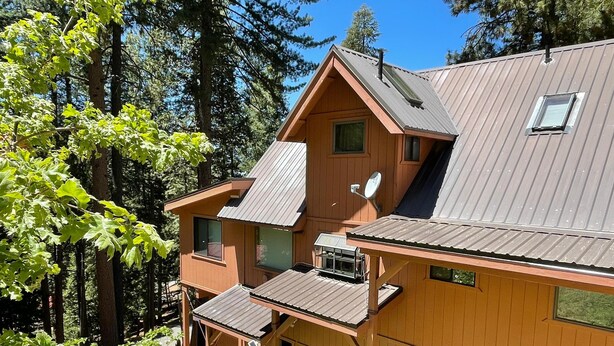 A wooden cabin with a sloped roof, a satellite dish, and a small window. - Chalet Yosemite (Yosemite National Park)