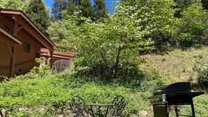 A rustic wooden cabin with a balcony, surrounded by lush greenery and trees. - Chalet Yosemite (Yosemite National Park)