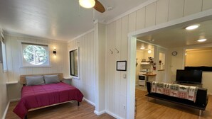 A bedroom with a bed, a window, a ceiling fan, and a view of the kitchen. - Chalet Yosemite (Yosemite National Park)