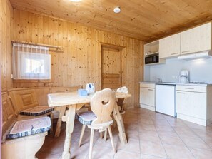 Cozy room with a wooden dining table, bench, and single chair, plus a small kitchen area with microwave and white cabinetry.